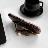 Protective leopard print phone case for iPhone 14 Plus with raised edges and convenient wrist strap attachment